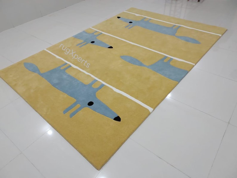 May include: A yellow rug with a white stripe pattern and blue fox silhouettes. The rug has the text "rugXperts" printed on it.