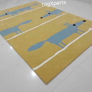 May include: A yellow rug with a repeating pattern of blue foxes. The foxes are outlined in white and have black eyes. The rug has a white border.