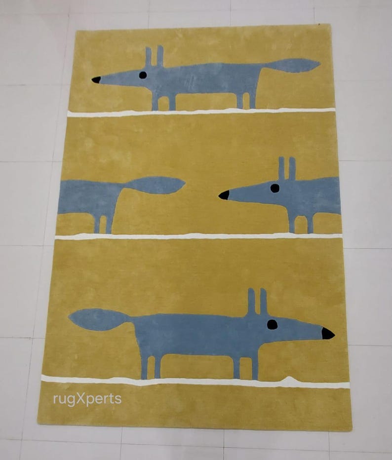 May include: A yellow rug with a repeating pattern of three blue stylized foxes. The rug has a white border and the text "rugXperts" is printed in the bottom left corner.