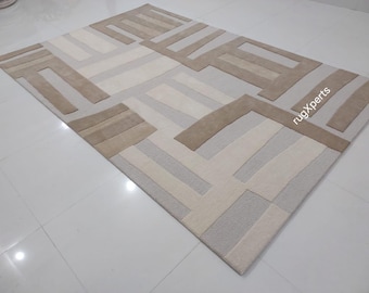 May include: A modern abstract area rug with a geometric design in shades of beige and white. The rug features a pattern of overlapping rectangles and squares.