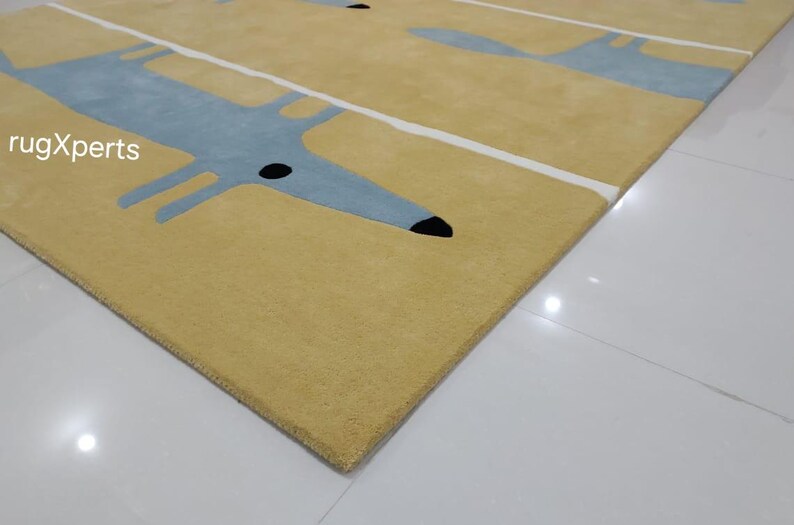 May include: A yellow rug with a repeating pattern of blue stylized dogs. The rug has white stripes running across it.