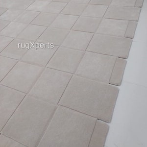 Pu&ograve; includere: Un grande tappeto modulare di colore grigio chiaro composto da quadrati singoli. Il tappeto &egrave; composto da 16 quadrati ed &egrave; disposto a griglia. Il tappeto si chiama "rugXperts".