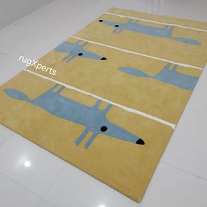 May include: A yellow rug with a repeating pattern of blue stylized foxes. The rug has white lines running across it.