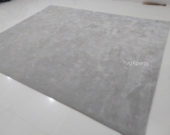 Puede incluir: Una alfombra gris claro con un patrón sutil y texturizado. La alfombra está hecha de un material suave y mullido y tiene un estilo contemporáneo.