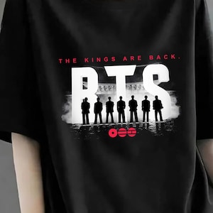 Könnte beinhalten: Schwarzes T-Shirt mit dem Text "THE KINGS ARE BACK." und den Buchstaben "BTS" in Weiß. Unter den Buchstaben befindet sich eine Silhouette von sieben Figuren. Der untere Teil des Shirts trägt den Text "300 DPI - FILE DOWNLOAD" in Rot.
