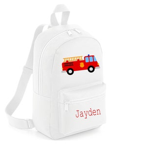 Può includere: Zaino in tela bianca con un'immagine di un camion dei pompieri rosso e il nome "Jayden" ricamato in rosso.