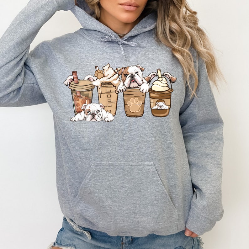 May include: Gray hooded sweatshirt with a graphic of four bulldogs peeking out of coffee cups. The bulldogs are white with brown spots and the coffee cups are brown with white lids.