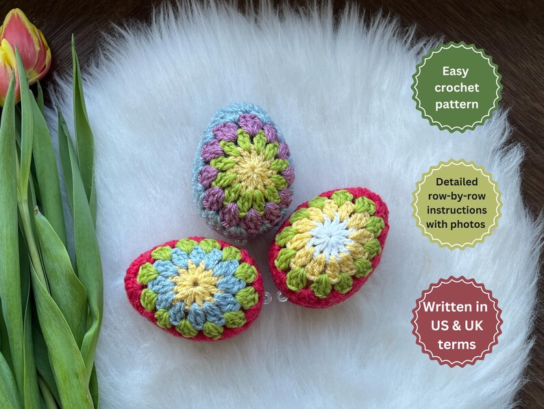 Three crocheted Easter eggs in pink, green, and blue with a white center. The eggs are on a white fluffy surface. Easy crochet pattern, detailed row-by-row instructions with photos, written in US & UK terms.