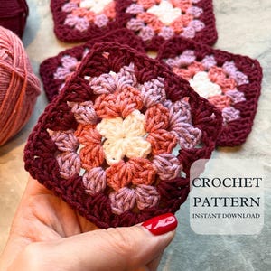 May include: Close-up of a crocheted granny square in shades of burgundy, pink, and cream. The square is held in a hand, with yarn and a crochet hook visible in the background. Text on the image reads "CROCHET PATTERN INSTANT DOWNLOAD."