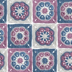 May include: A close-up of a crocheted blanket composed of square motifs. Each square features a central floral design in shades of blue, pink, and white, surrounded by a contrasting border. The overall pattern is symmetrical and visually appealing.