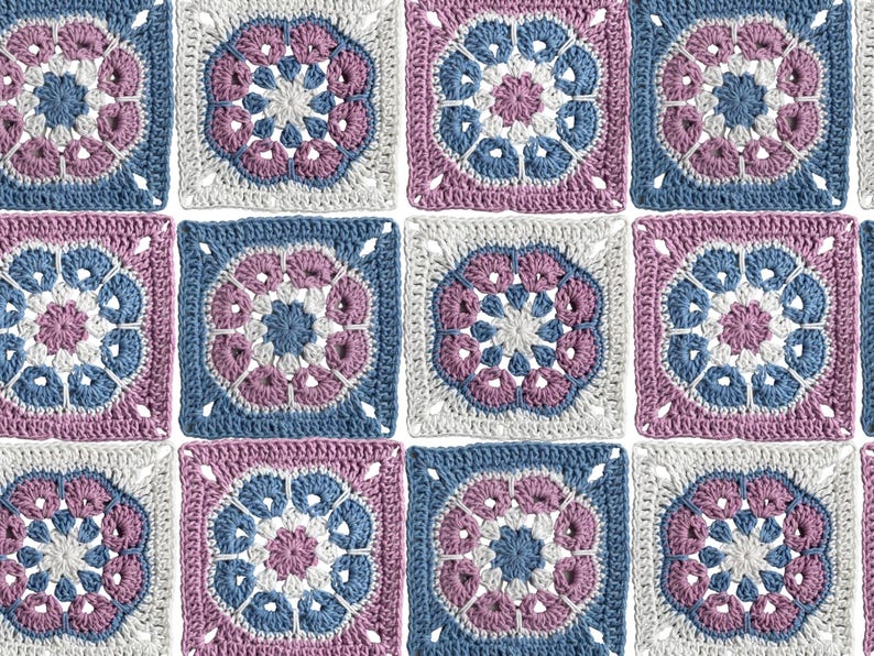 May include: A close-up of a crocheted blanket composed of square motifs. Each square features a central floral design in shades of blue, pink, and white, surrounded by a contrasting border. The overall pattern is symmetrical and visually appealing.