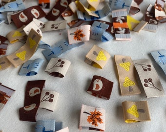 May include: Assortment of fabric scraps with various autumnal designs, including birds, mushrooms, leaves, and berries. The scraps are in shades of brown, yellow, blue, and white.