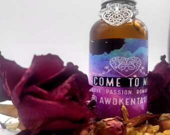 May include: A small glass bottle with a silver cap and a silver heart charm. The bottle is filled with a clear liquid and has a label that reads "Come to Me Love Passion Roman Awoken Tarot". The bottle is surrounded by dried rose petals.