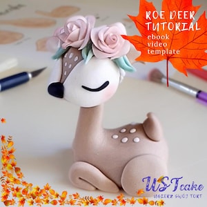 Puede incluir: Figura de ciervo artesanal con una corona floral. El ciervo es de color marrón claro con manchas blancas y ojos cerrados. El texto "KOE DEER TUTORIAL" es visible en una hoja naranja. La figura es probablemente un adorno para tartas.