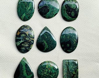 May include: Nine polished gemstones in various shapes, including oval, round, teardrop, and rectangular. The stones feature a dark green color with intricate patterns and swirls, showcasing natural variations.