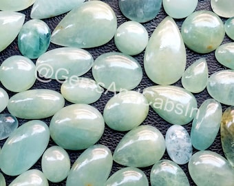 Könnte beinhalten: Eine Sammlung von hellblauen Aquamarin-Edelsteinen in verschiedenen Formen und Größen. Die Edelsteine sind glatt und poliert und haben einen perlmuttartigen Glanz.