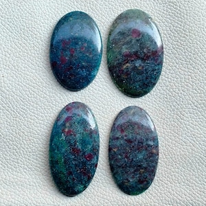 May include: Four oval gemstones with a polished surface. The stones display a blend of deep teal, green, and burgundy hues. The gemstones are arranged in a square, highlighting their unique colour variations.