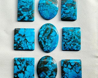 Puede incluir: Nueve piedras preciosas pulidas de varias formas: rectangulares, ovaladas y cuadradas. Las piedras presentan un llamativo color azul turquesa con vetas marrón oscuro, creando un efecto marmolado. Las piedras preciosas están dispuestas sobre una superficie blanca, mostrando sus patrones y texturas únicos.