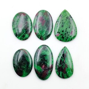 May include: Six polished cabochons of ruby in zoisite, featuring a mix of vibrant green, deep red, and black speckled patterns. The collection includes four oval-shaped stones and two teardrop-shaped stones, all with a smooth, reflective surface.