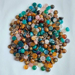 Puede incluir: Un gran surtido de cabujones coloridos, incluyendo ojo de tigre, turquesa y ágata. Los cabujones son todos redondos y tienen un acabado liso y pulido.