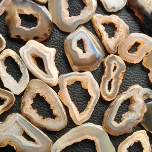 May include: A collection of agate slices with natural crystal formations. The slices are various shades of brown and white with a translucent quality. The agate slices have a unique, organic shape and are perfect for crafting or display.