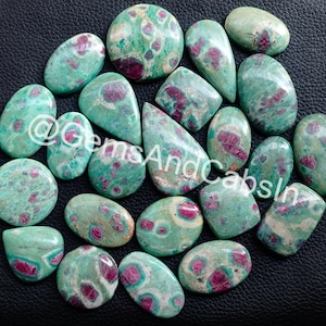 Può includere: Una collezione di 18 cabochon di zoisite rubino verde e rosa. Le pietre sono di forma ovale e a goccia e hanno un motivo maculato.