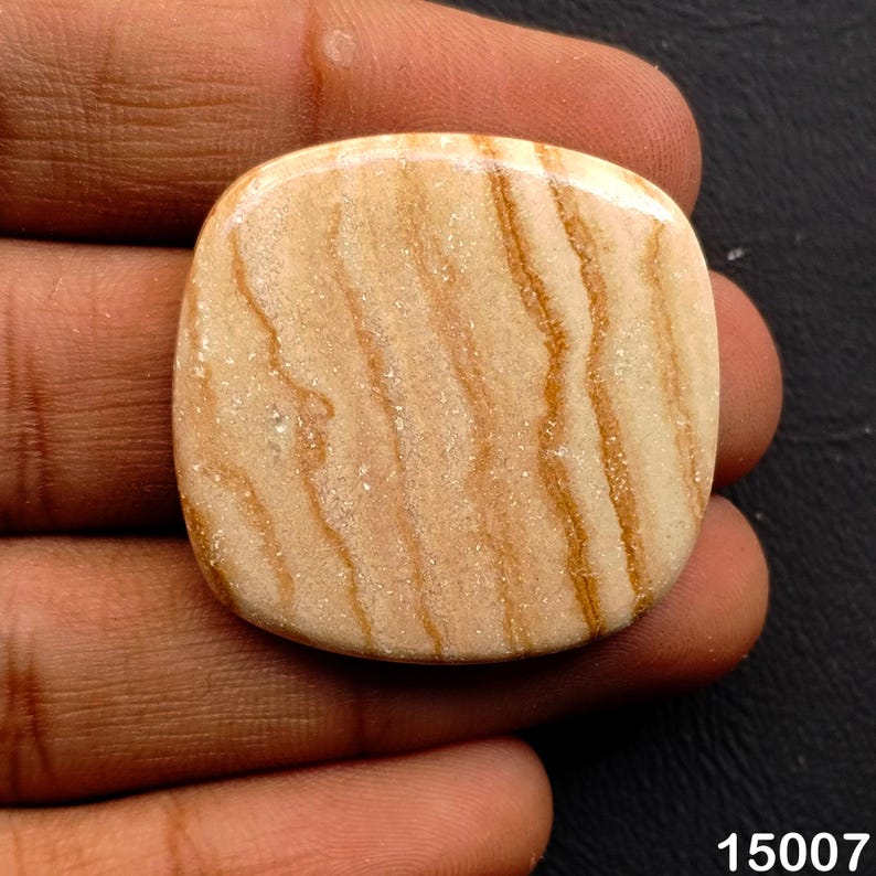 Puede incluir: Una gema pulida, de forma cuadrada, con un color base beige claro y prominentes vetas marrones onduladas. La piedra tiene una superficie lisa y redondeada. El n&uacute;mero "15007" es visible en la esquina inferior derecha.
