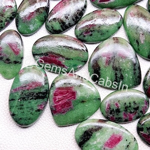 Może przedstawiać: Kolekcja owalnych zielonych, czarnych i różowych kamieni szlachetnych. Kamienie szlachetne mają gładkie, wypolerowane wykończenie i są ułożone na białym tle.