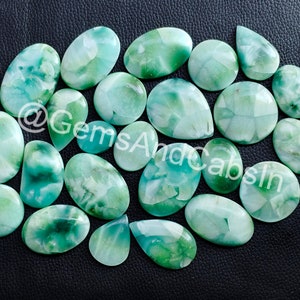 May include: A collection of 17 green and white cabochon gemstones. The stones are oval and pear shaped and have a cloudy, marbled appearance.