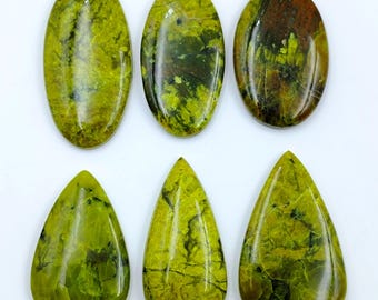 Puede incluir: Seis piedras preciosas pulidas con un acabado liso y brillante. La fila superior presenta tres piedras de forma ovalada, mientras que la fila inferior contiene tres piedras en forma de lágrima. Cada pieza muestra un color verde lima vibrante.