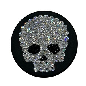 May include: A black and white skull design made of rhinestones on a black background.
