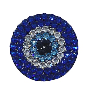 May include: A blue and white evil eye charm with rhinestones. The charm is round and has a black center.