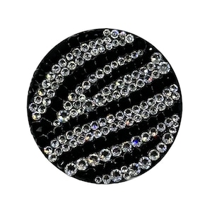 May include: A round, black phone grip with a swirl design made of clear rhinestones.