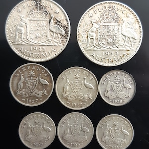 May include: A selection of vintage Australian coins, including Florins and Sixpence, dating from the 1920s to the 1940s. The coins display the Australian coat of arms, featuring a kangaroo and emu. The word "AUSTRALIA" is inscribed on the coins.