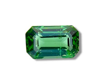 May include: A vibrant green emerald cut gemstone with a slightly bluish hue.