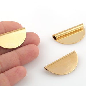 May include: Three gold-colored metal half-circle shapes with a flat surface and a slightly curved edge. The half-circles are about 1 inch in diameter.