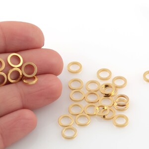 以下が含まれることがあります： 金色のジャンプリングの山、いくつかは手に、いくつかは白い表面に散らばっています。