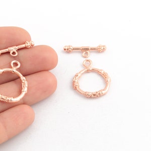Puede incluir: Cierre de palanca de oro rosa con un anillo redondo decorativo. El cierre está hecho de metal y tiene un acabado pulido.