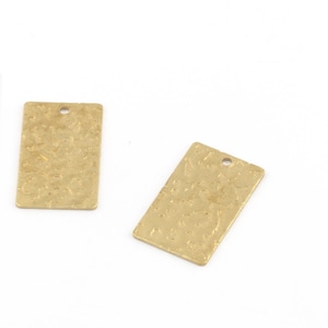 May include: Two gold-colored metal rectangular tags with a textured surface and a hole at the top. The tags are approximately 1 inch in length.