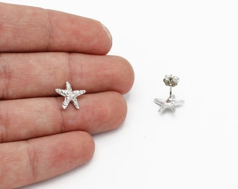 May include: A pair of silver starfish stud earrings. The earrings are small and delicate, and they have a textured surface.