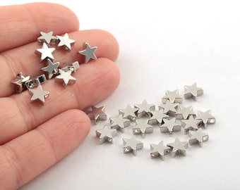 Könnte beinhalten: Ein Haufen silberner, sternförmiger Metallperlen. Die Perlen haben ein Loch in der Mitte zum Auf fädeln.