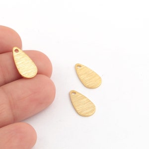 May include: Three gold-colored metal teardrop-shaped charms with a small hole at the top for attaching to jewelry or other crafts.