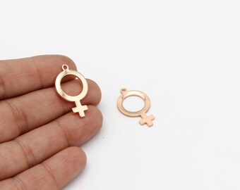May include: Two gold-colored metal charms in the shape of the female gender symbol. The charms have a circular loop at the top for attaching to a necklace or bracelet.