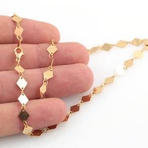 May include: A gold chain necklace with a diamond-shaped link pattern.
