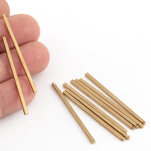 May include: A set of ten gold-colored metal rods with rounded ends. The rods are approximately 2 inches long and have a square cross-section.