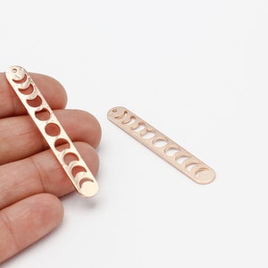 May include: Two gold-toned metal charms shaped like a long rectangle with a series of crescent moon cutouts. The charms are perfect for jewelry making.