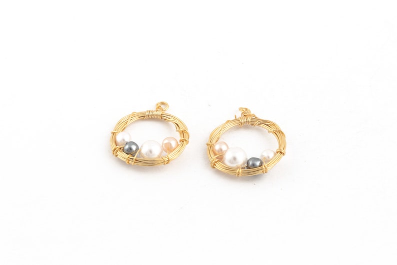 May include: Two gold wire circles with white, pink, and gray pearls attached. The circles are about 1 inch in diameter.