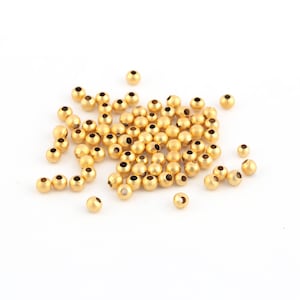 May include: A pile of small, round, gold-colored beads. The beads are smooth and have a shiny finish.