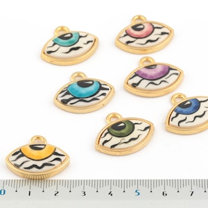 May include: Seven gold-tone eye charms with black and white zebra stripes and colorful irises. The charms are approximately 1 inch in length.