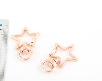 May include: Two gold-toned metal star-shaped clasps with a swivel ring. The clasps are approximately 2.5 cm in diameter.
